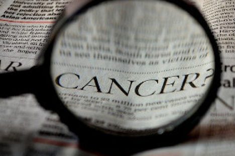 Lupe über Zeitung mit dem englischen Wort für Krebs